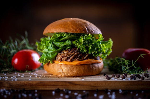 Craft pork sandwich with cheddar, lettuce and purple onion on wooden background