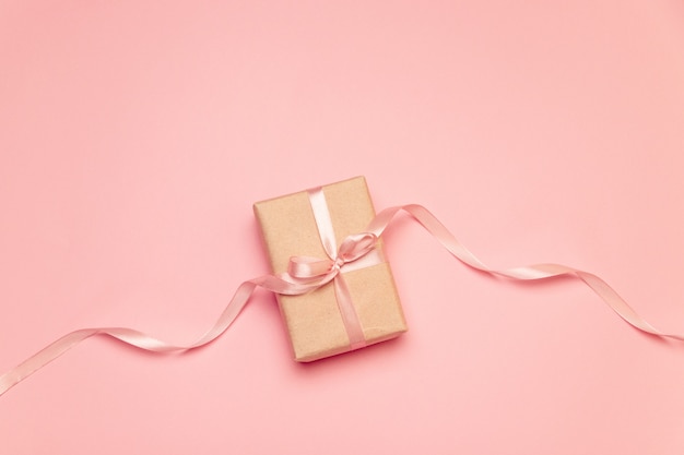 Craft present box with pink pastel bow ribbon on pink canvas 