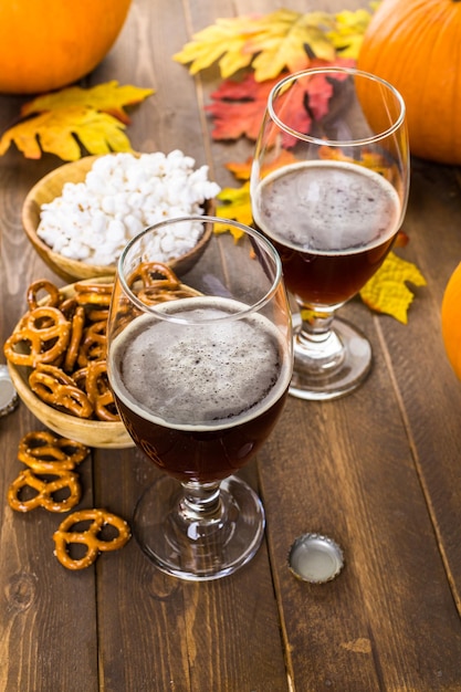 Foto birra artigianale alla zucca in bicchieri da birra con salatini salati e popcorn.