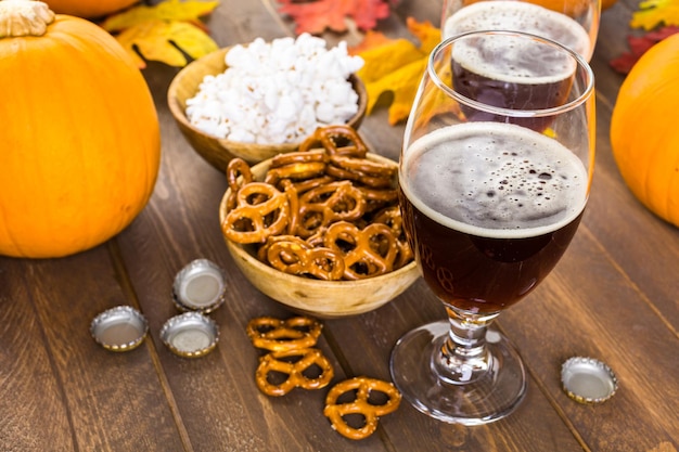 Craft pumpkin beer in beer glasses with salty pretzels and popcorn.