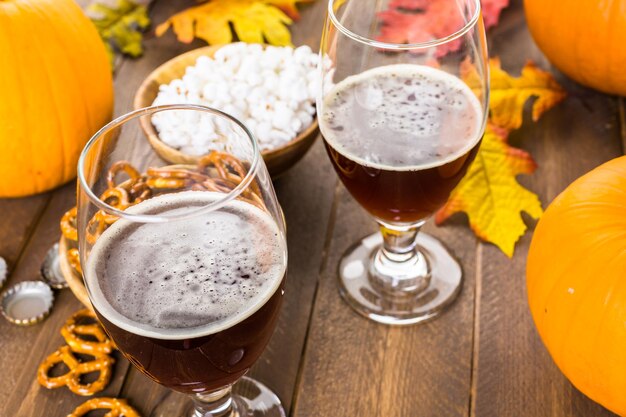 Craft pumpkin beer in beer glasses with salty pretzels and popcorn.