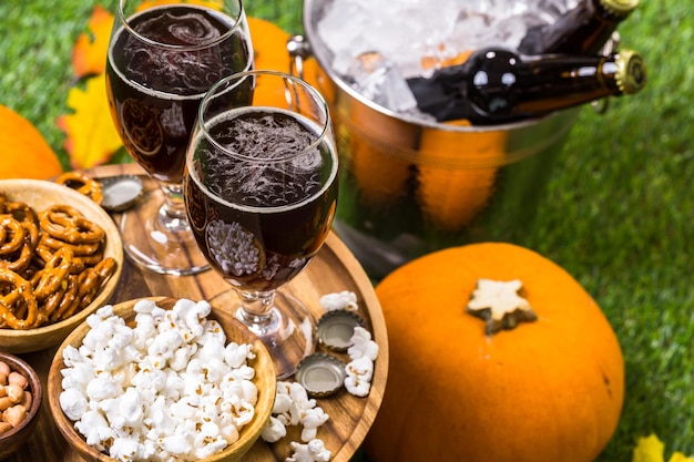 Craft pumpkin beer in beer glasses with salty pretzels and popcorn.