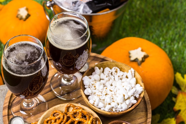 Craft pumpkin beer in beer glasses with salty pretzels and popcorn.