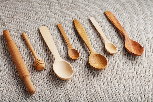 Foto cucchiai artigianali realizzati con diversi tipi di legno giacciono in fila su un tessuto di tela di canapa