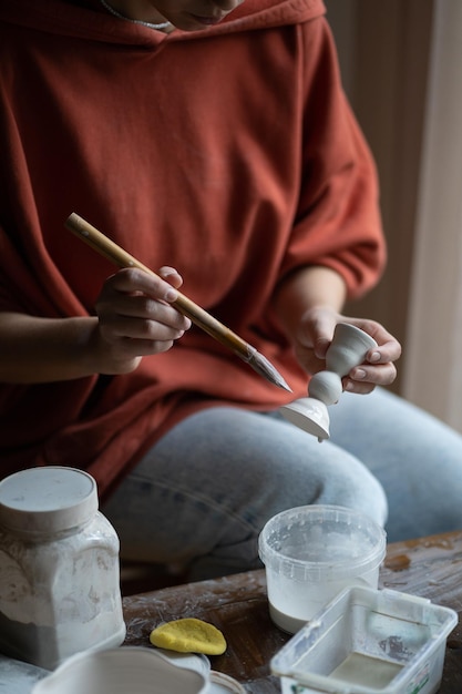 Photo craft woman holds clay product created using brush and water to smooth connections pottery material