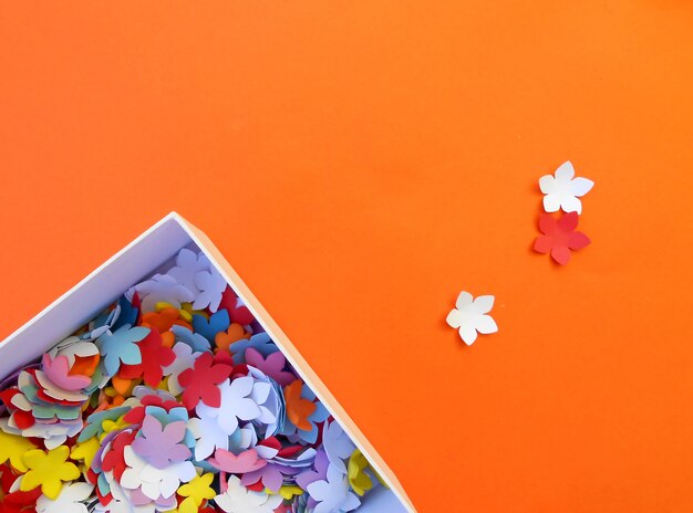 Crafts box with paper flowers on orange background