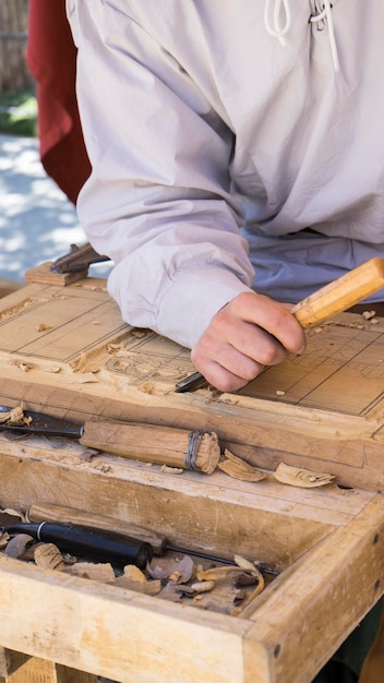 ремесленник, вырезающий дерево на средневековой ярмарке, столярные инструменты