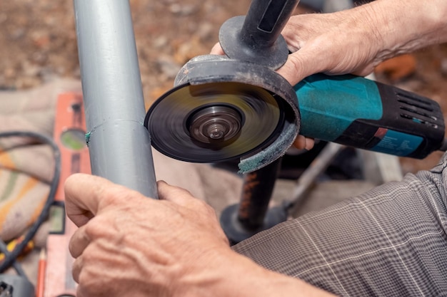 A craftsman cuts a PVC pipe using an xangle grinder