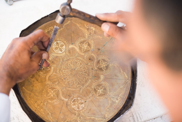 トレイに職人の彫刻模様。中央アジアのマスター。手動銅ミンティング