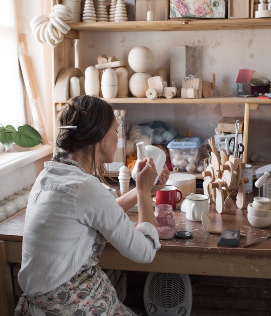 A craftsman girl paints wooden toys in the workshop