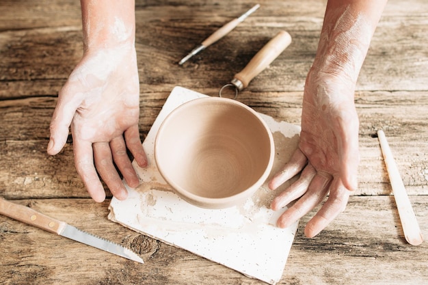 Craftsman hands with pottery and tools on table