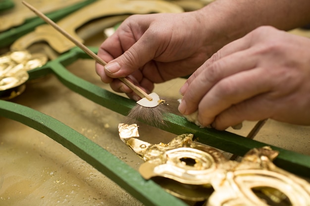 Mani dell'artigiano che lavorano con una foglia d'oro.