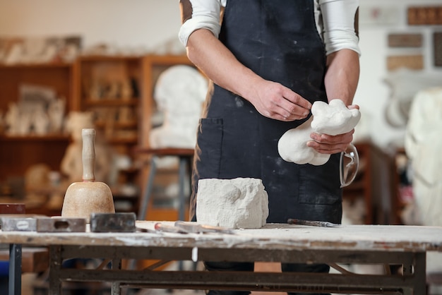 Craftsman hands working with stone sculptor at creative workplace in the atmospheric studio.