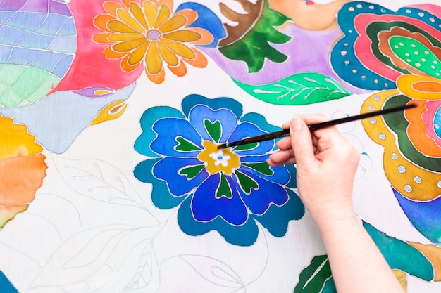 Photo craftsman paints flower in batik on silk canvas