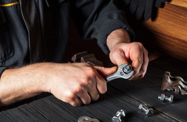 Craftsman tightens a nut with a wrench on a close-up of a bolt in a workshop