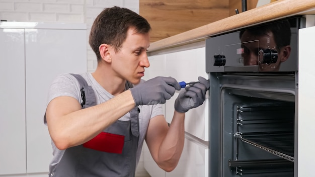 Photo craftsman twists screws on oven to find defect in kitchen