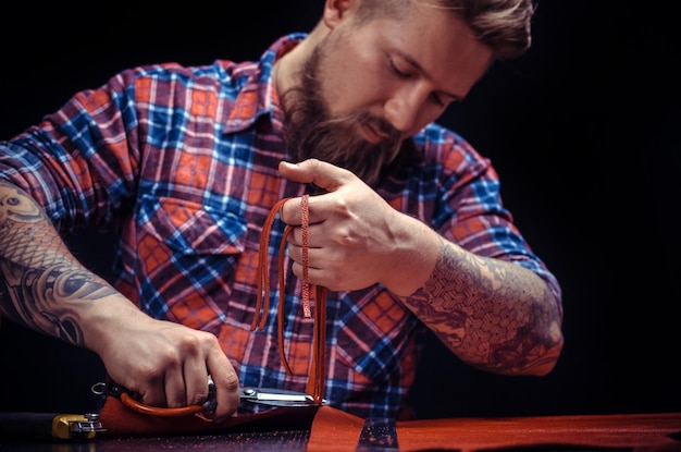 Craftsman working with leather produce a leatherwork