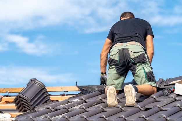 Photo a craftsman works on the roof of a house with a ceramic tile