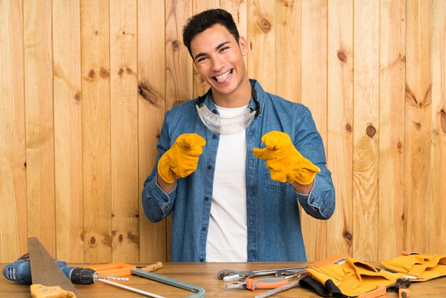 Craftsmen man over wood wall points finger at you