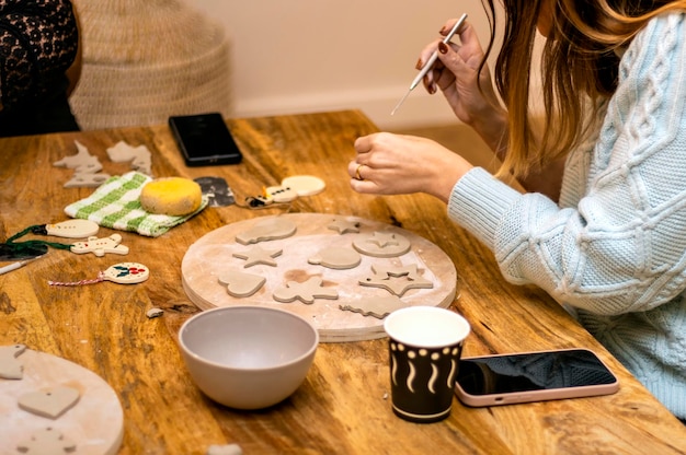 職人のコンセプト屋内で陶器を作る若い女性が座ってモデリング ツールを使用してパターンを作成します