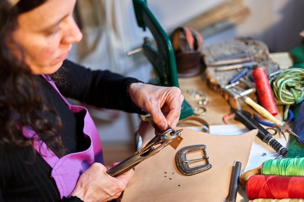 Craftswoman drilling leather