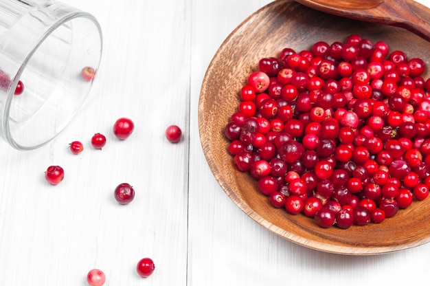 Cranberries in wooden bowl on white surface