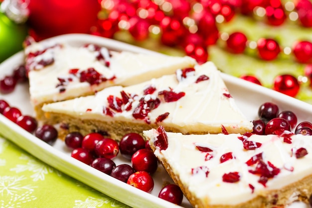 Cranberry bliss bar made with chunks of white chocolate and dried cranberries, topped with sweet cream cheese icing.