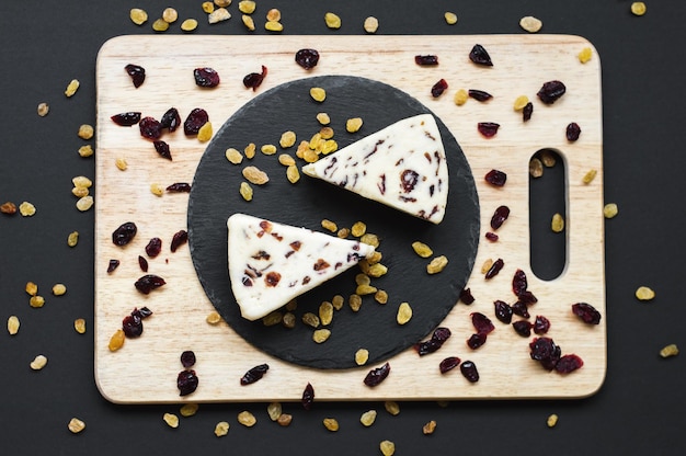 Cranberry cheese and many dried cranberries and raisins on black slate and wooden board