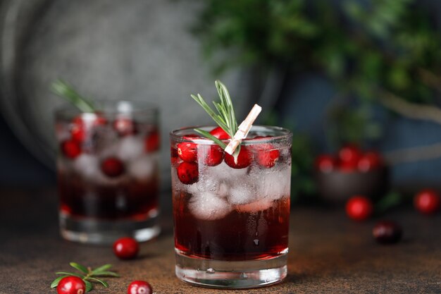 Cocktail di mirtilli rossi con ghiaccio. bevanda di mirtillo rosso di natale in bicchieri decorati con zucchero e rosmarino