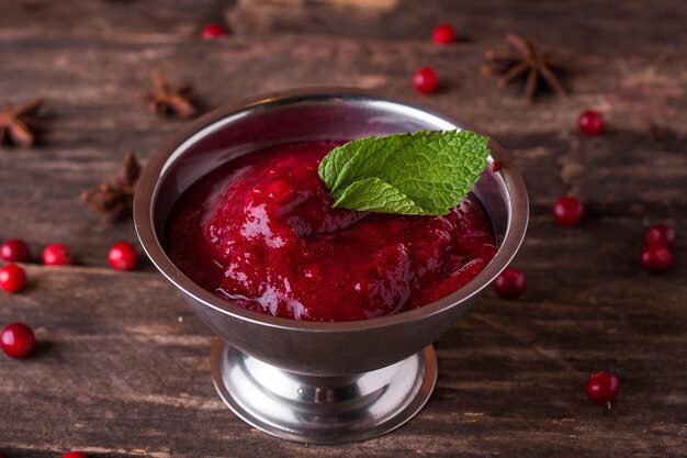 Cranberry jam in a bowl on a wooden table