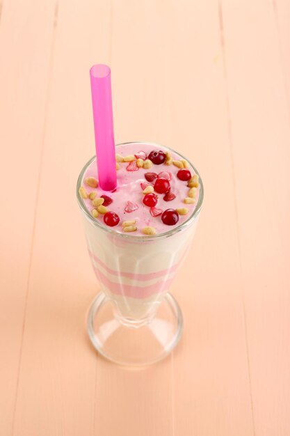 Cranberry milk dessert in glass, on color wooden background