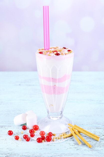 Cranberry milk shake in glass, on color wooden background