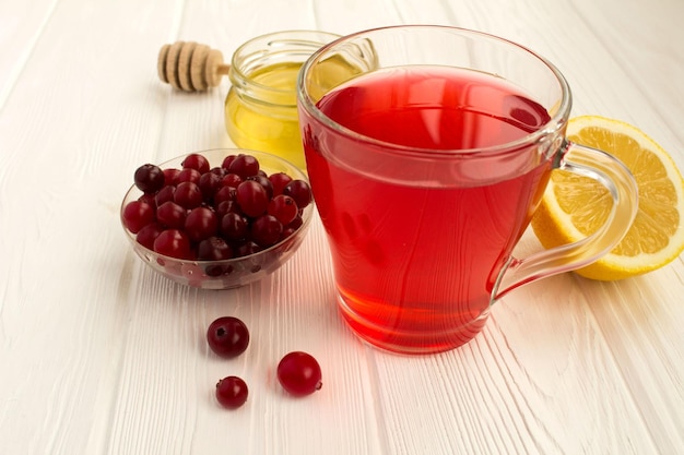 Cranberry mors honey and lemon on the white wooden background