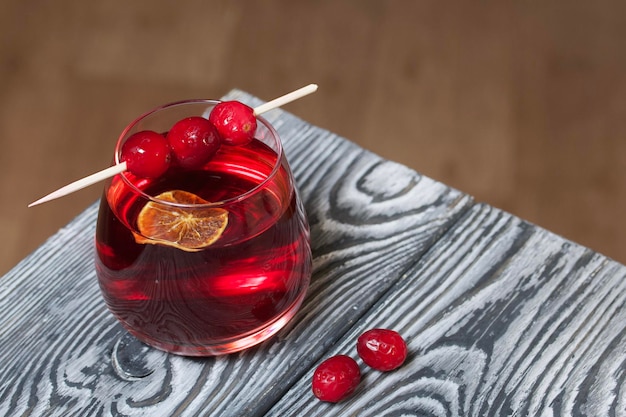 Photo cranberry punch garnished with a slice of dry orange cranberries on a wooden skewer