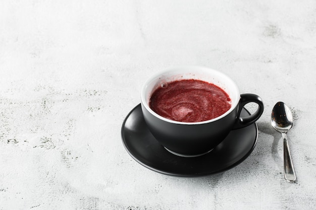 Cranberry, red or raspberry tea in dark cup isolated on bright marble background. Overhead view, copy space. Advertising for cafe menu. Coffee shop menu. Horizontal photo.