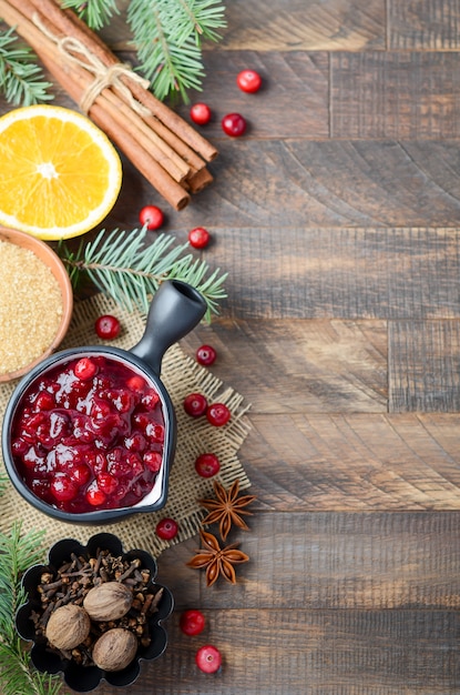 Cranberry sauce with ingredients on a wooden table