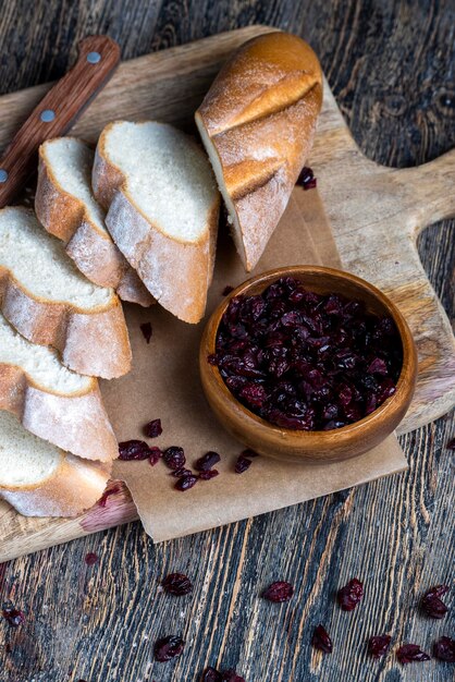 Cranberry and sliced soft fresh baguette on a cutting board and table