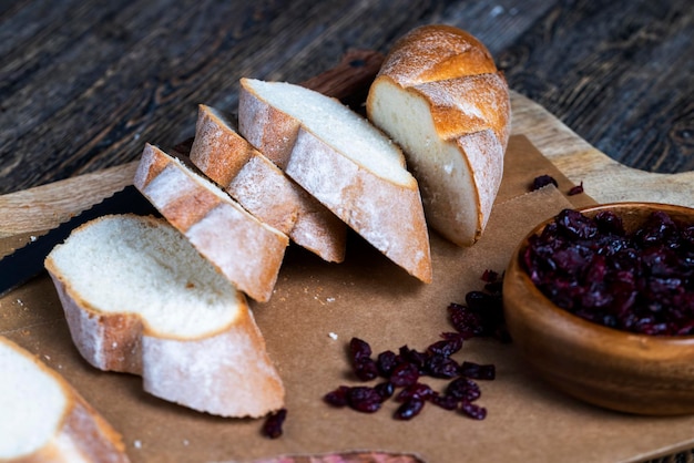 Cranberry and sliced soft fresh baguette on a cutting board and table