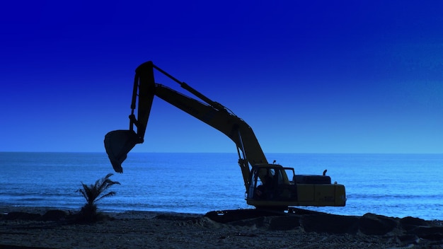 Crane on beach against sea and blue sky