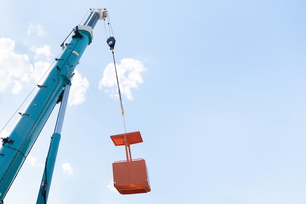 Crane boom with lifting mechanism and yellow cradle in the sky