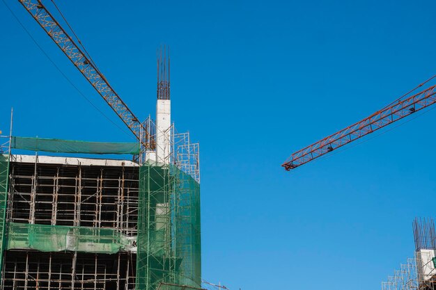 Photo crane and building construction site against blue sky metal construction of unfinished building