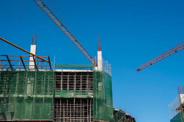 Crane and building construction site against blue sky