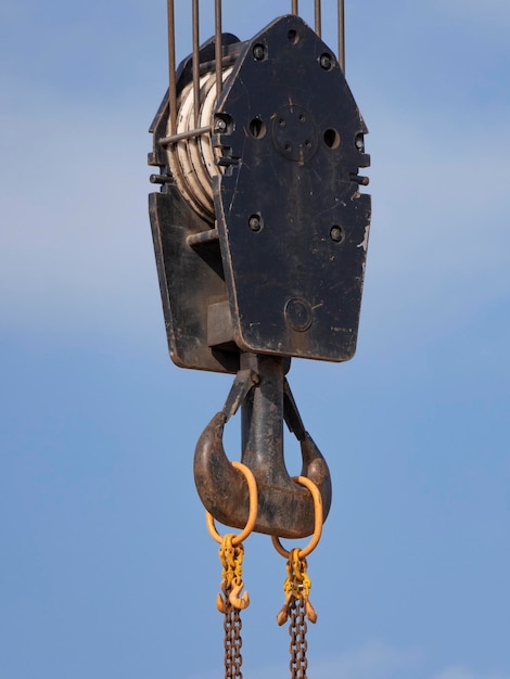 Crane hook with red and white stripes hanging blue sky in background