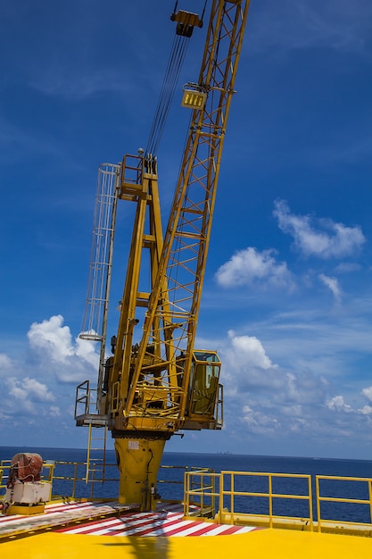 Crane lifting offshore industrial oil and gas sea and blue sky.