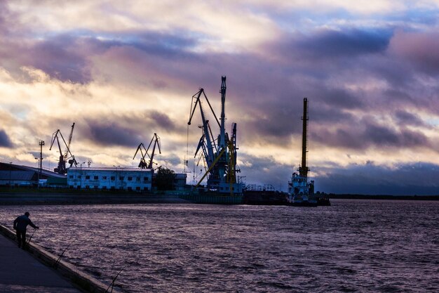 Cranes by sea during sunset