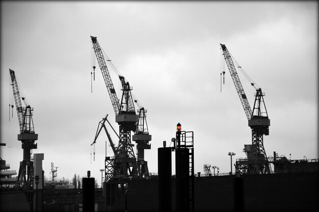 Photo cranes at commercial dock against sky at dusk