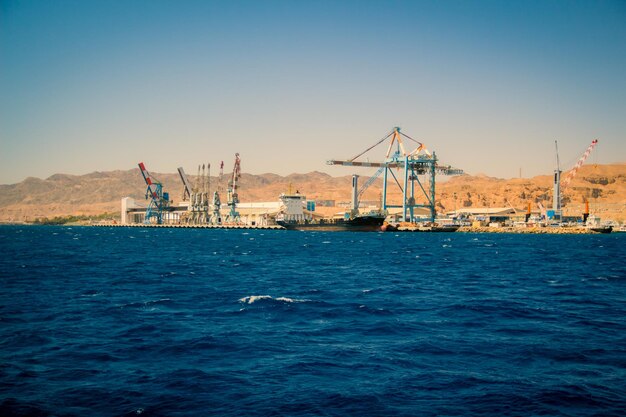 cranes at harbor against clear blue sky