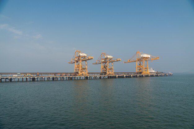 Photo cranes at pier by sea against sky