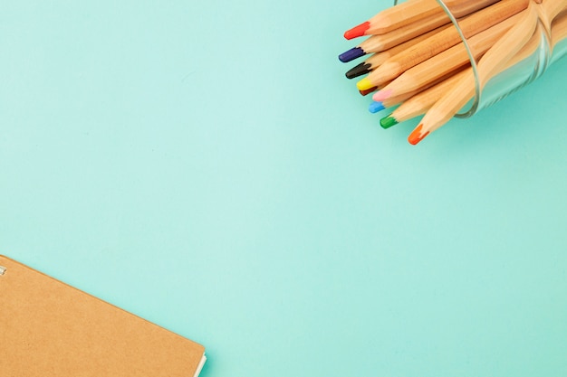 Crayon in glass With a notebook on blue