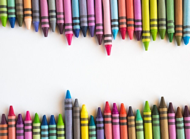 Crayons and pastels lined up in rainbow isolated on white background